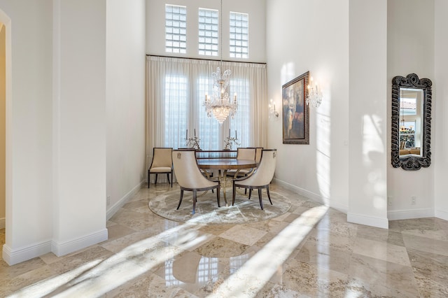 dining area with a towering ceiling and a notable chandelier