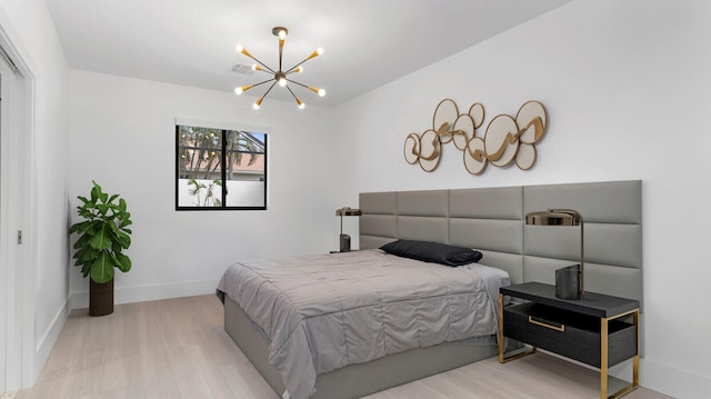 bedroom with light hardwood / wood-style flooring and a chandelier