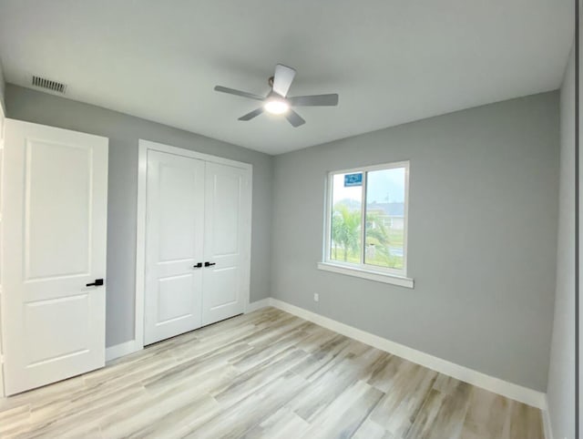 unfurnished bedroom with light hardwood / wood-style floors, a closet, and ceiling fan