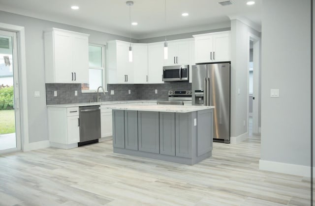 kitchen featuring white cabinetry, decorative light fixtures, a center island, and appliances with stainless steel finishes