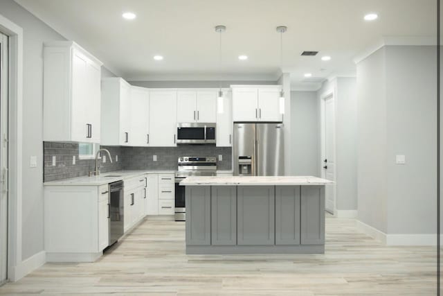 kitchen featuring sink, hanging light fixtures, a kitchen island, stainless steel appliances, and white cabinets