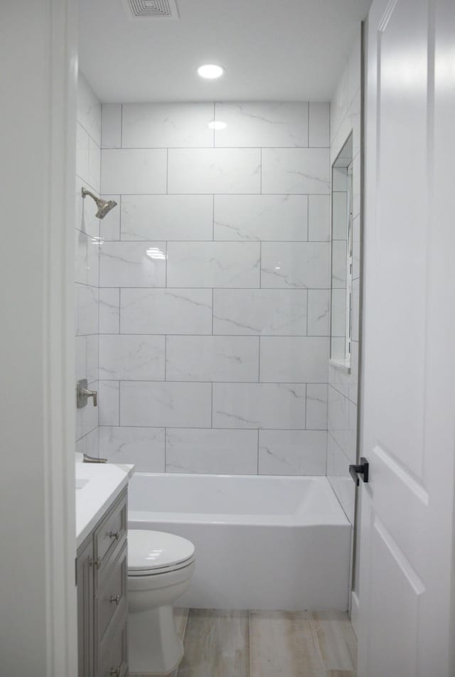 full bathroom with tiled shower / bath combo, vanity, and toilet