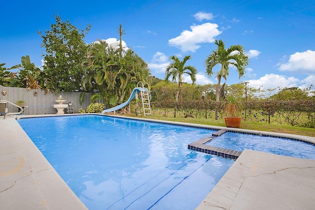 view of swimming pool featuring a pool with connected hot tub, a water slide, and fence