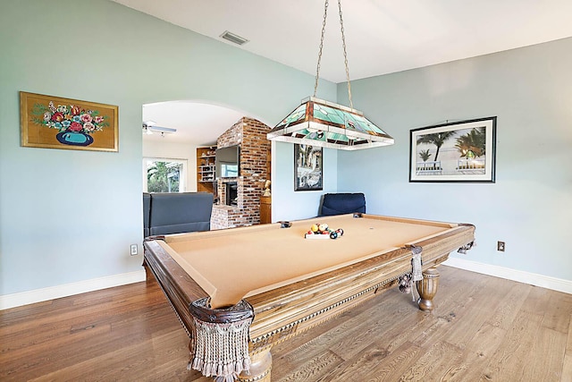 rec room featuring visible vents, arched walkways, wood finished floors, pool table, and a brick fireplace