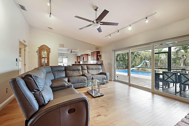 living room featuring lofted ceiling, light wood-type flooring, visible vents, and a ceiling fan