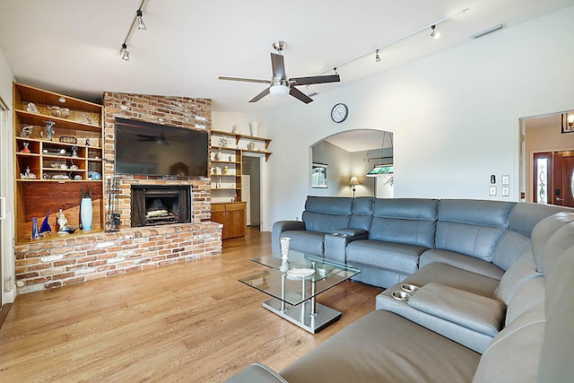 living room with a ceiling fan, arched walkways, a fireplace, and wood finished floors