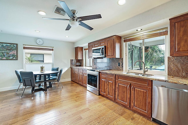 kitchen featuring light wood-style flooring, decorative backsplash, stainless steel appliances, and a sink