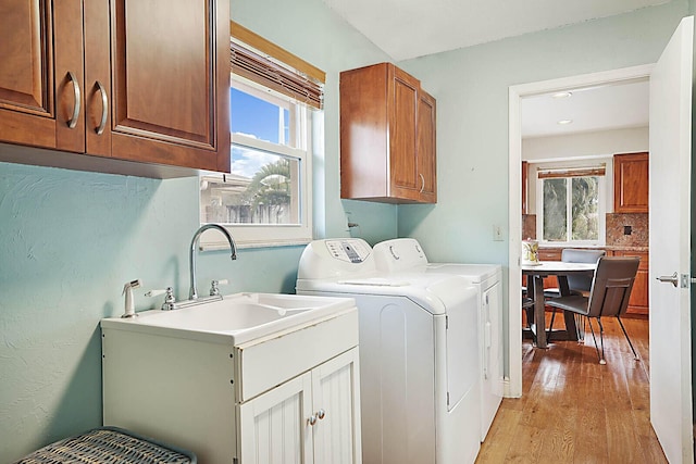 laundry room with light wood-style floors, washing machine and dryer, and cabinet space