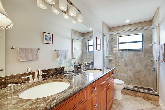 full bathroom featuring a sink, a shower stall, toilet, and double vanity