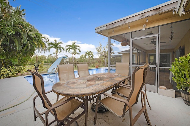 view of patio / terrace featuring outdoor dining area, fence, a sunroom, and an outdoor pool