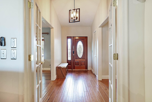 entryway with an inviting chandelier, baseboards, and hardwood / wood-style floors