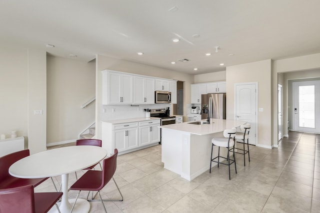 kitchen featuring a center island with sink, white cabinets, sink, and appliances with stainless steel finishes