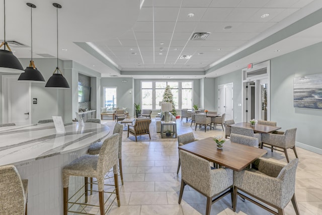 dining space featuring a raised ceiling, a paneled ceiling, and light tile patterned floors