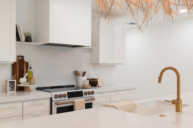 kitchen featuring backsplash, white cabinetry, sink, and range