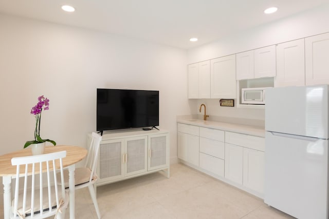 kitchen featuring white cabinets, light tile patterned floors, white appliances, and sink