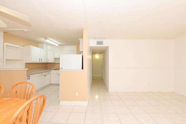 kitchen with white cabinets, white refrigerator, and light tile patterned flooring