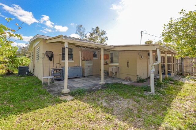 back of property with a lawn, a patio area, and central air condition unit