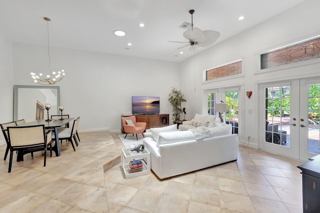 living room with ceiling fan with notable chandelier, a towering ceiling, and french doors