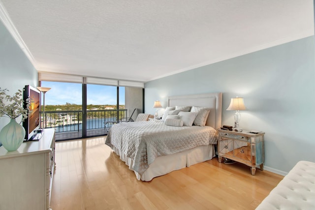 bedroom with access to exterior, wood-type flooring, a wall of windows, and crown molding