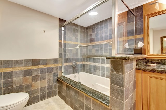 full bathroom featuring vanity, tile patterned flooring, toilet, enclosed tub / shower combo, and tile walls