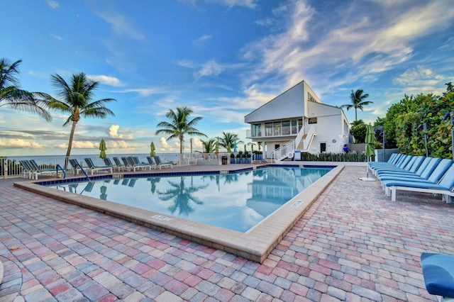 view of swimming pool with a water view and a patio area