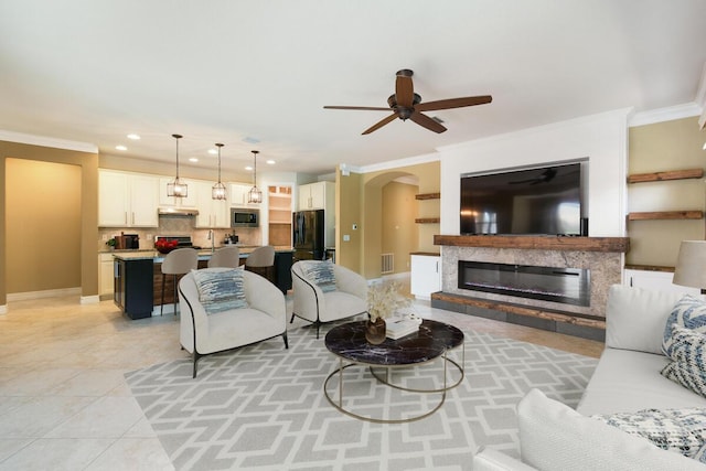 tiled living room with ceiling fan, ornamental molding, and a premium fireplace