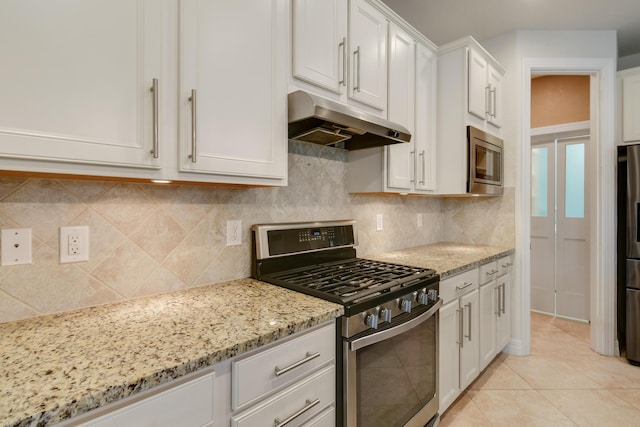 kitchen with white cabinetry, light stone counters, backsplash, light tile patterned floors, and appliances with stainless steel finishes