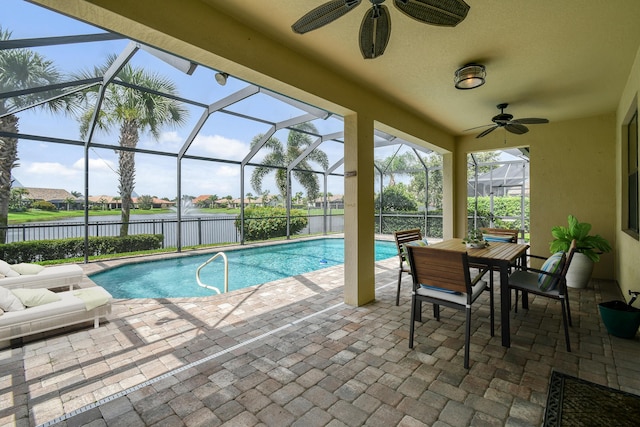 view of pool with glass enclosure, ceiling fan, a patio area, and a water view