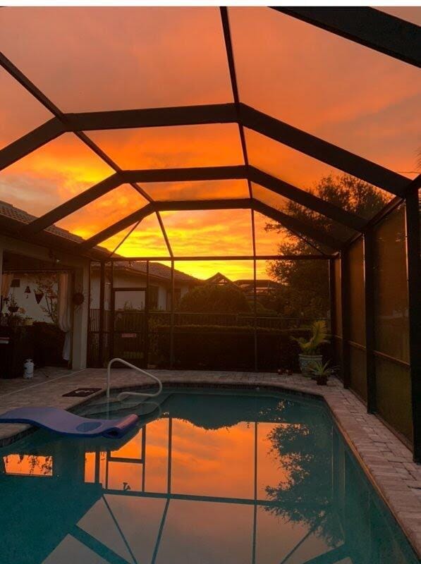 pool at dusk featuring a hot tub and a lanai