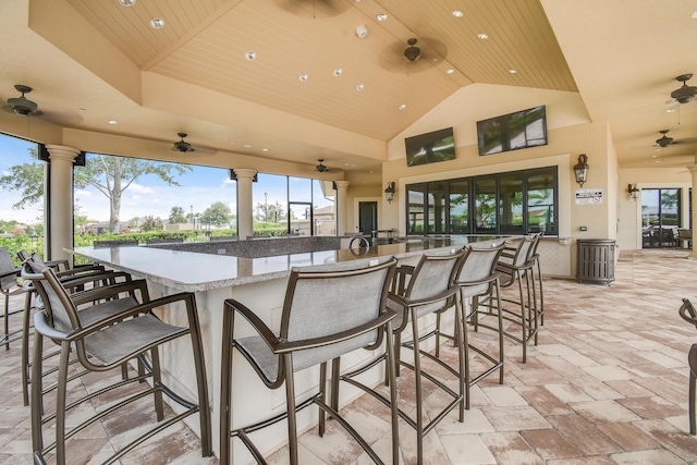 view of patio / terrace featuring exterior bar, a water view, and ceiling fan