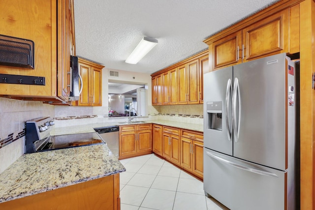 kitchen featuring appliances with stainless steel finishes, light stone counters, a textured ceiling, sink, and light tile patterned floors