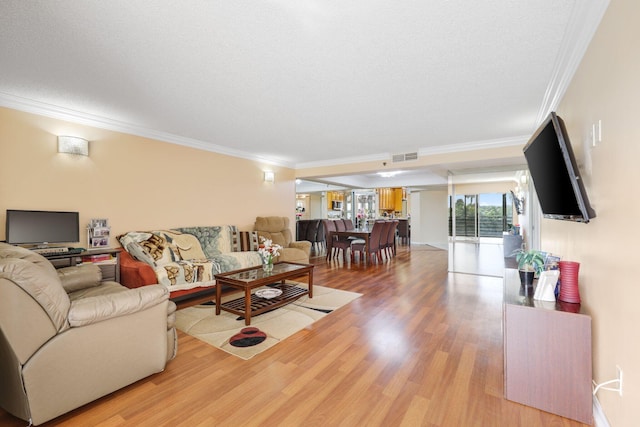 living room featuring wood-type flooring, ornamental molding, and a textured ceiling