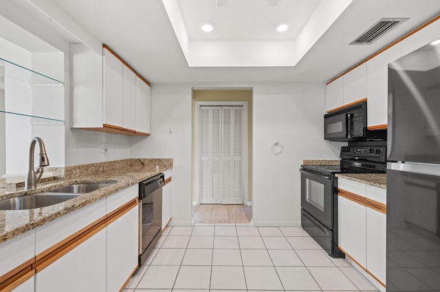 kitchen with kitchen peninsula, stainless steel appliances, sink, light tile patterned floors, and white cabinetry