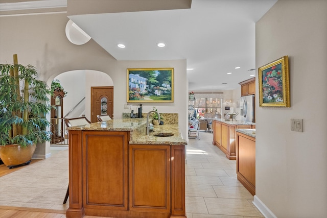 bar with sink, stainless steel fridge, light tile patterned flooring, and light stone countertops