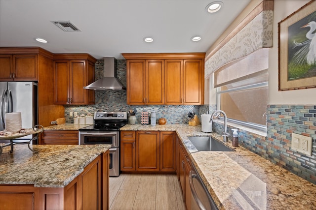 kitchen with light stone counters, stainless steel appliances, wall chimney exhaust hood, and sink