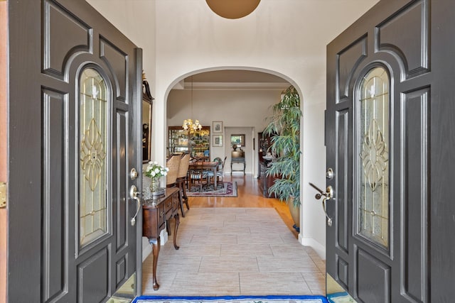 entrance foyer featuring crown molding, a chandelier, and light hardwood / wood-style flooring