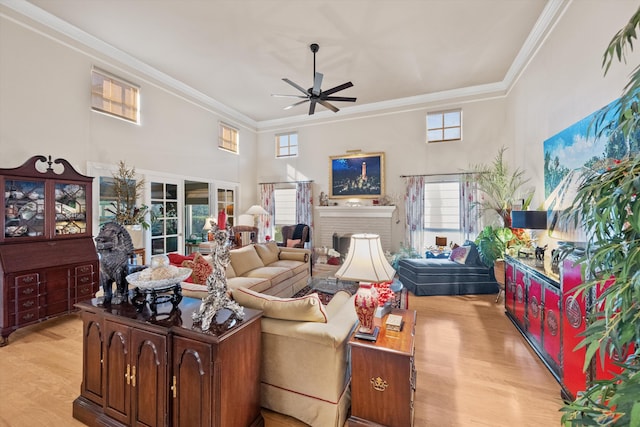 living room featuring a brick fireplace, ceiling fan, ornamental molding, and plenty of natural light