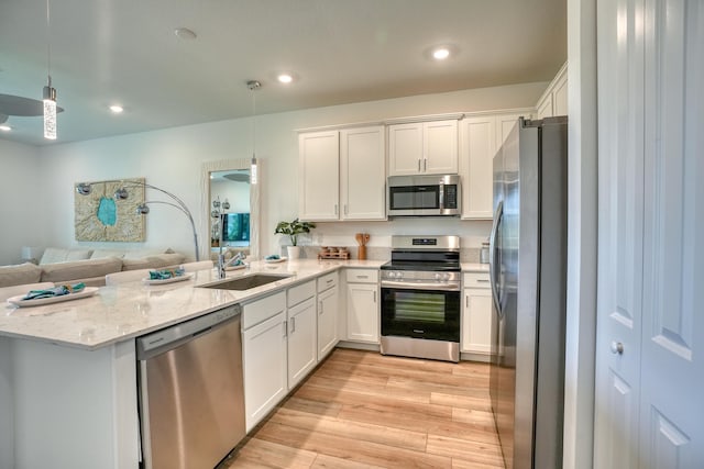 kitchen featuring appliances with stainless steel finishes, white cabinetry, pendant lighting, and sink