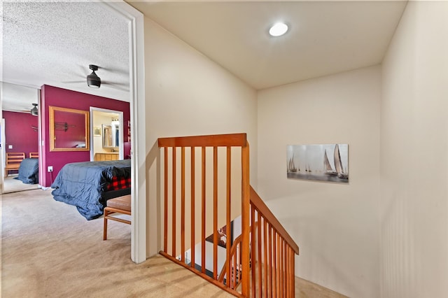 staircase with carpet, ceiling fan, and a textured ceiling