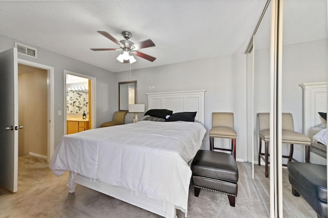 carpeted bedroom featuring a textured ceiling, ensuite bathroom, and ceiling fan