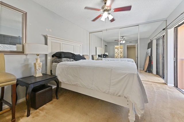 bedroom featuring light carpet, a textured ceiling, and ceiling fan