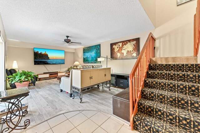 living room with ceiling fan, a textured ceiling, and light hardwood / wood-style flooring