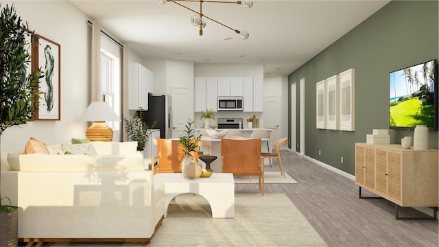 living room with light wood-style flooring, baseboards, and an inviting chandelier