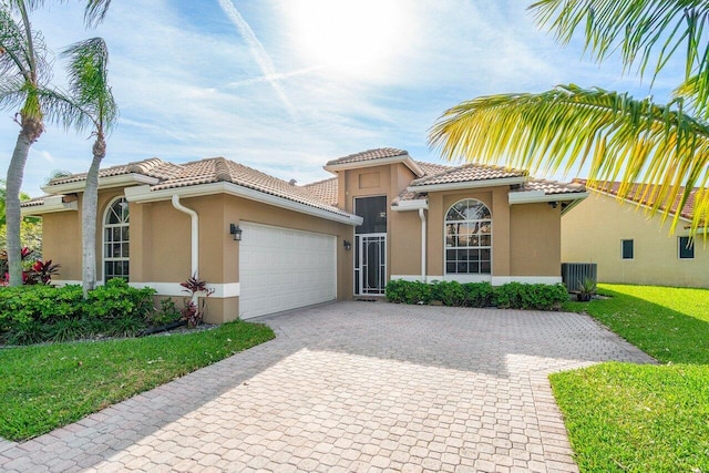 mediterranean / spanish house with a garage, cooling unit, and a front yard