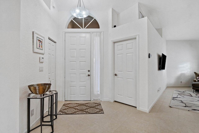 foyer with an inviting chandelier, light tile patterned floors, and high vaulted ceiling