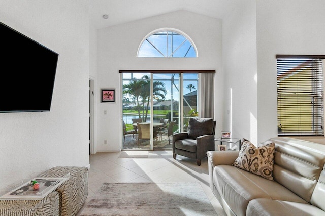 living room featuring a water view, high vaulted ceiling, and light tile patterned floors