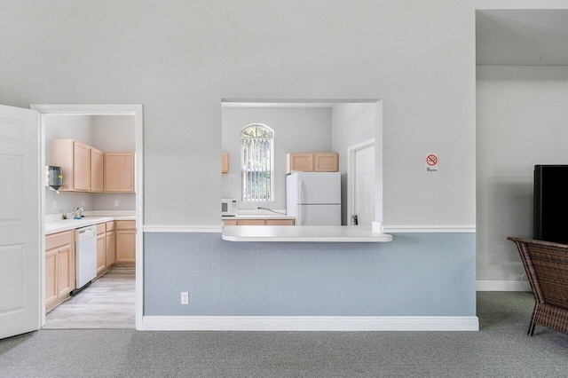 kitchen featuring white appliances, light carpet, and light brown cabinets