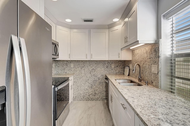 kitchen featuring light stone countertops, sink, stainless steel appliances, backsplash, and white cabinets