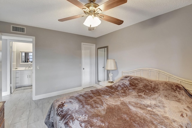 bedroom with ceiling fan, sink, a textured ceiling, and a closet