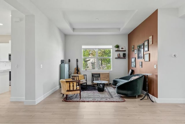 sitting room featuring light hardwood / wood-style floors, a raised ceiling, and a fireplace